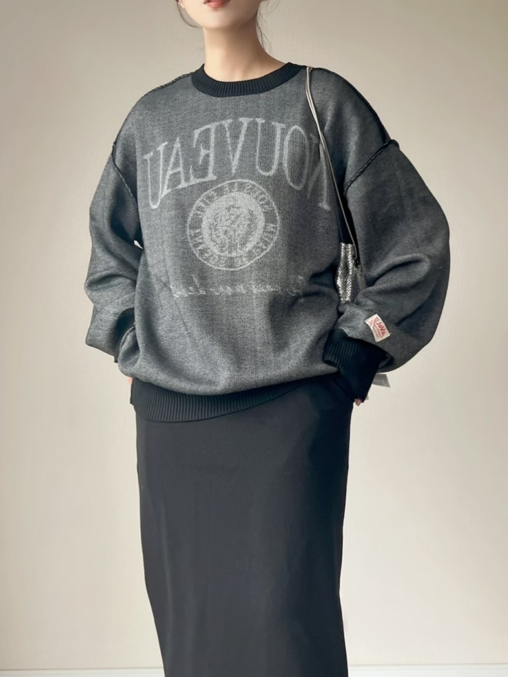 ブラック系のニット/セーター、ブラック系のスカート、ホワイト系のスニーカーを着用したレディースの秋コーディネートの2枚目の写真