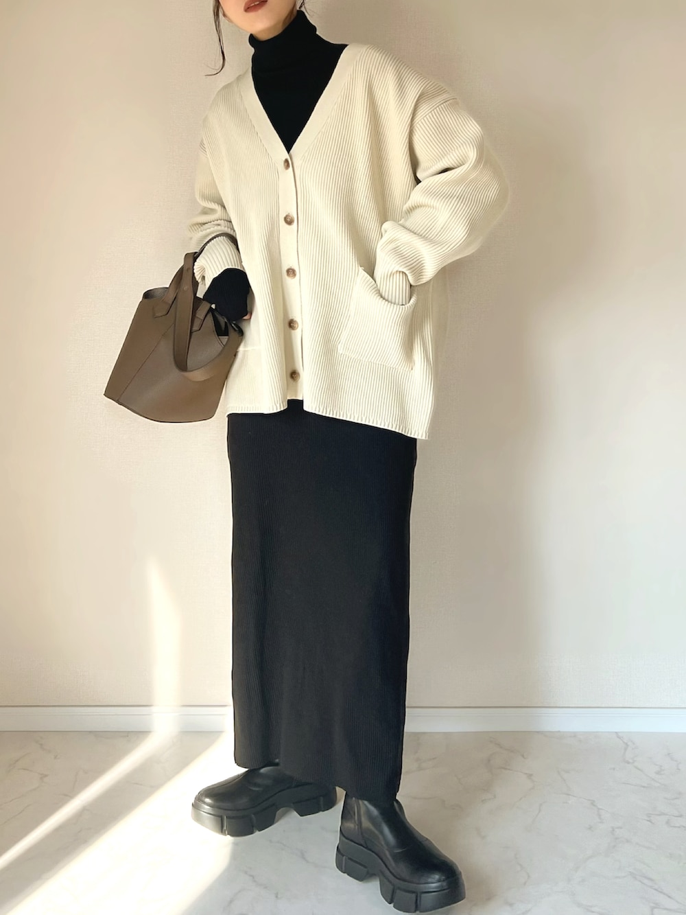 ホワイト系のカーディガン/ボレロ、ブラック系のニット/セーター、ブラック系のブーツを着用したレディースの冬コーディネートの2枚目の写真