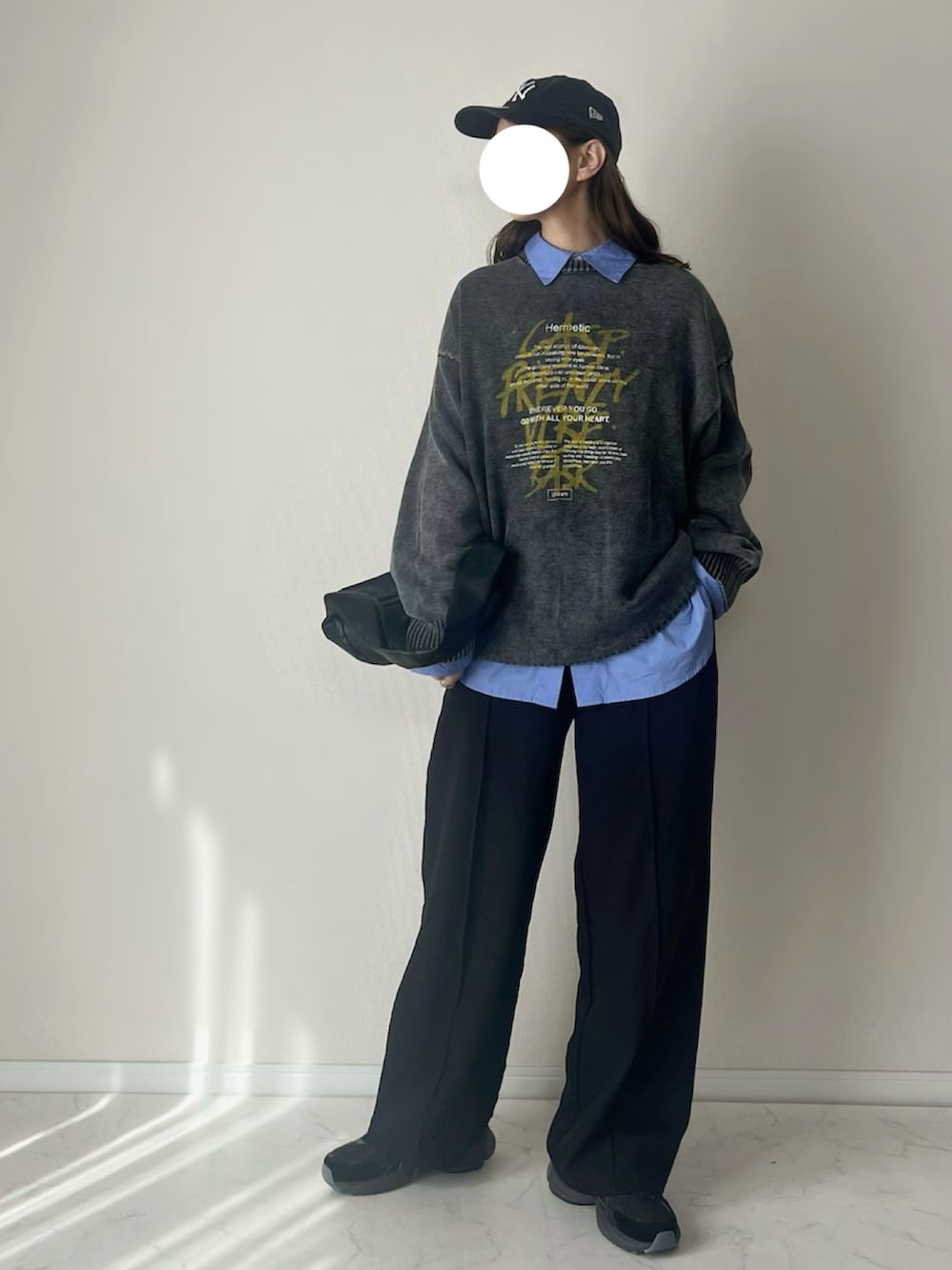 ブラック系のニット/セーター、ブルー系のシャツ/ブラウス、ブラック系のスラックスを着用したレディースの冬コーディネートの2枚目の写真