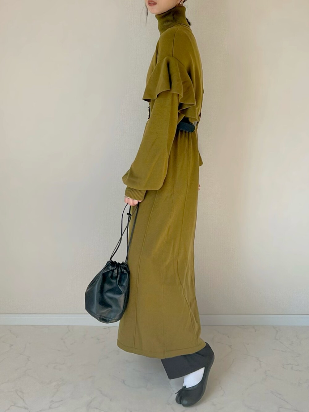 グリーン系のワンピース、ブラック系のハンドバッグを着用したレディースの秋コーディネートの3枚目の写真