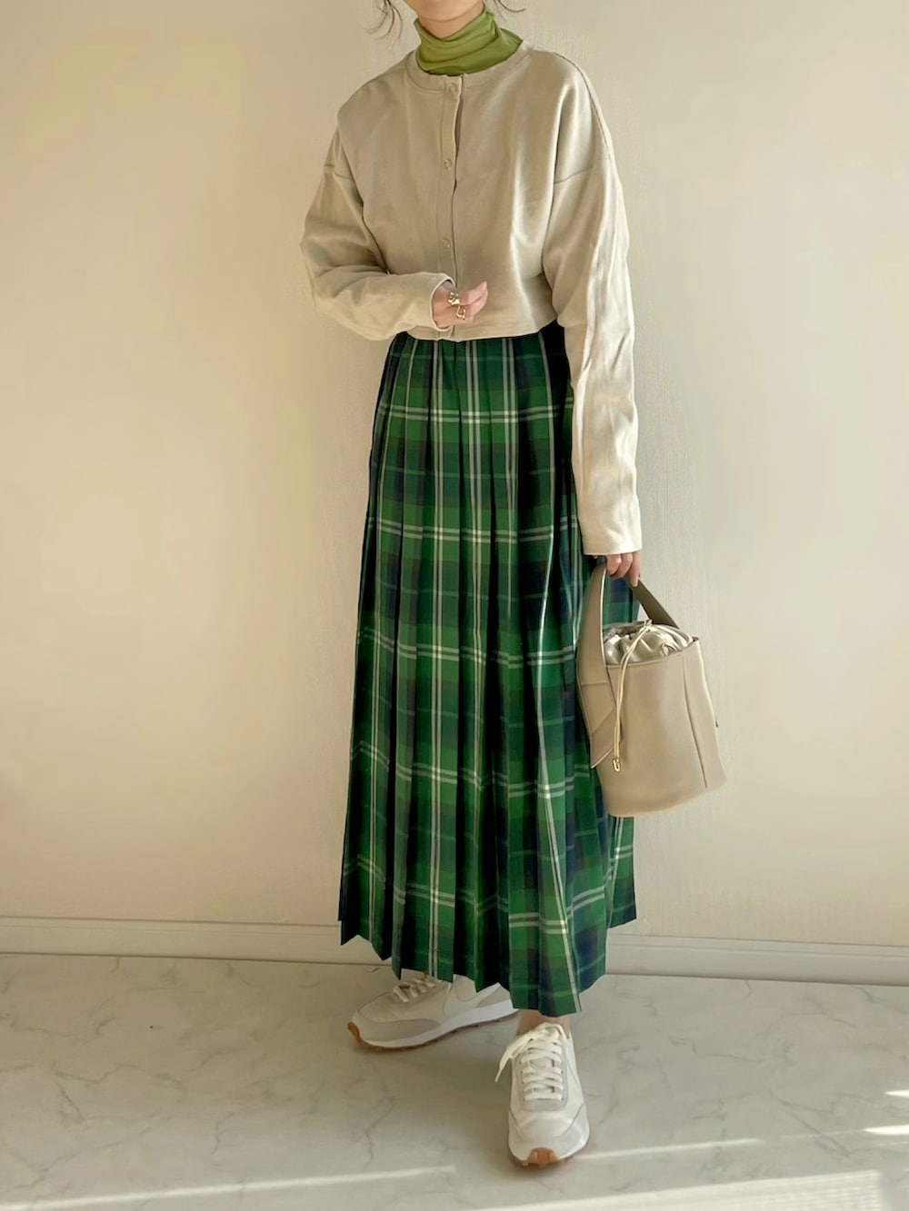 グリーン系のスカート、ベージュ系のカーディガン/ボレロ、グリーン系のTシャツ/カットソーを着用したレディースの冬コーディネートの3枚目の写真