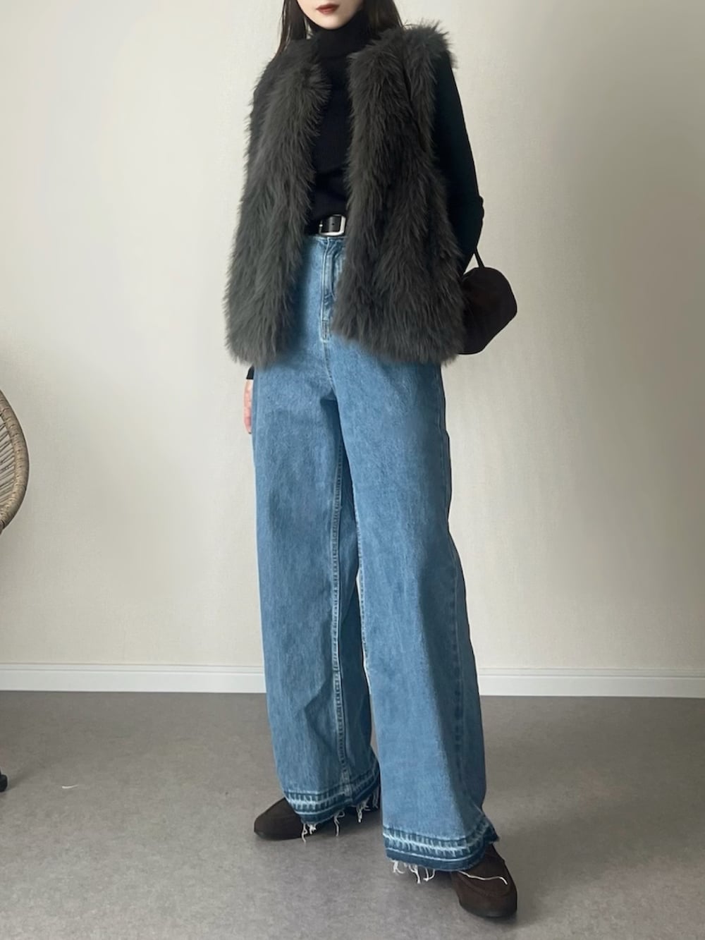 グレー系のベスト、ブルー系のデニムパンツ、ブラウン系のローファーを着用したレディースの冬コーディネートの2枚目の写真