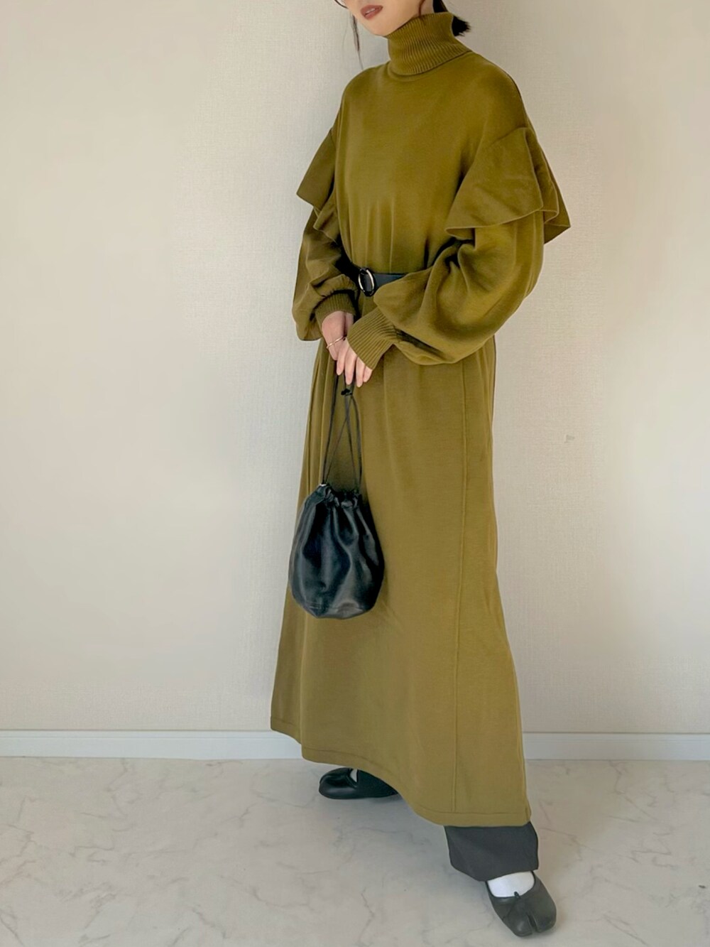 グリーン系のワンピース、ブラック系のハンドバッグを着用したレディースの秋コーディネートの2枚目の写真