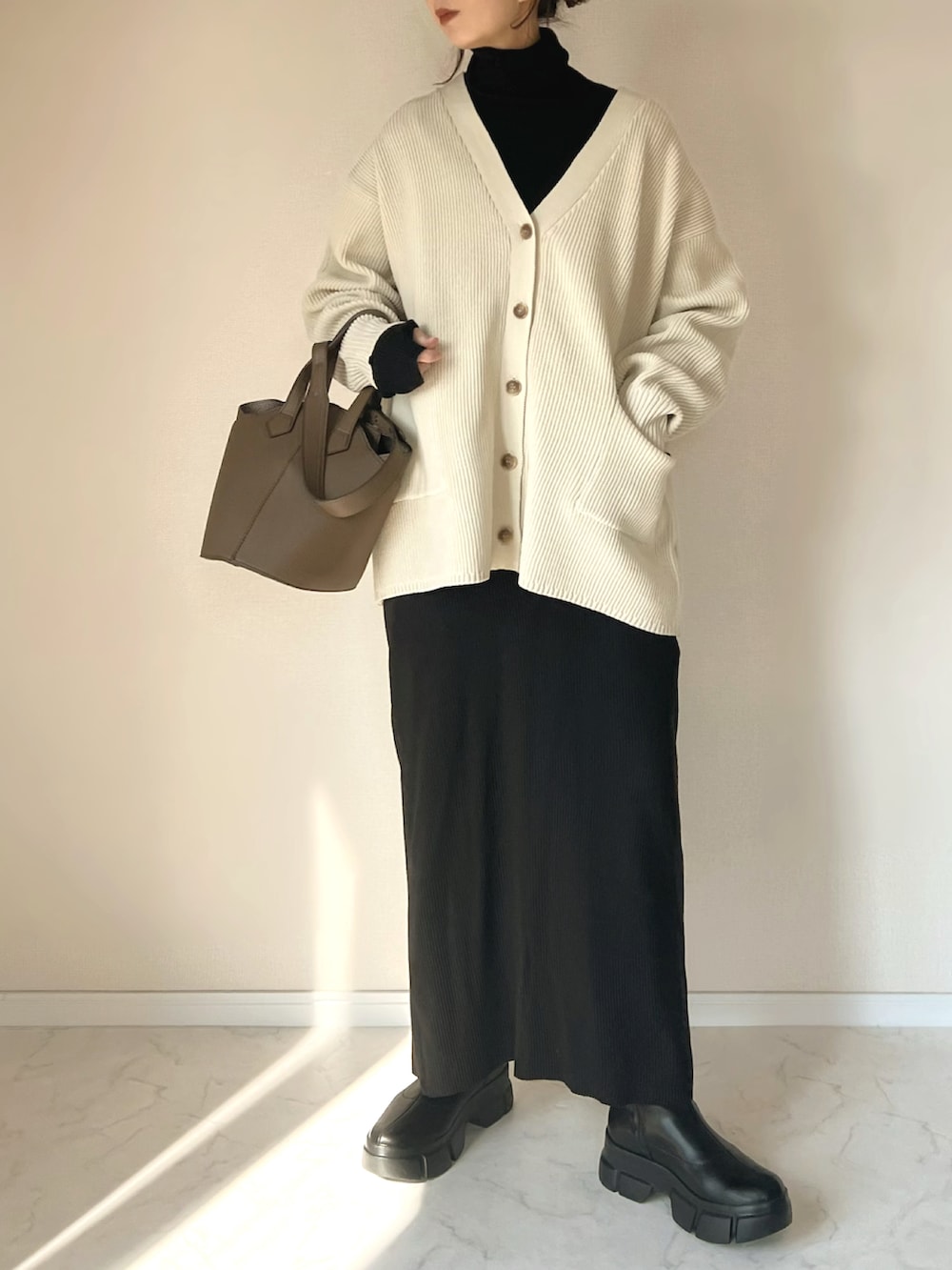 ホワイト系のカーディガン/ボレロ、ブラック系のニット/セーター、ブラック系のブーツを着用したレディースの冬コーディネートの3枚目の写真