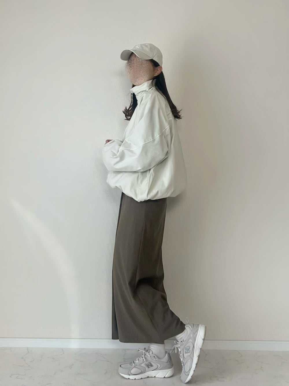 ホワイト系のブルゾン、ベージュ系のスニーカー、ベージュ系のキャップを着用したレディースの秋コーディネートの3枚目の写真