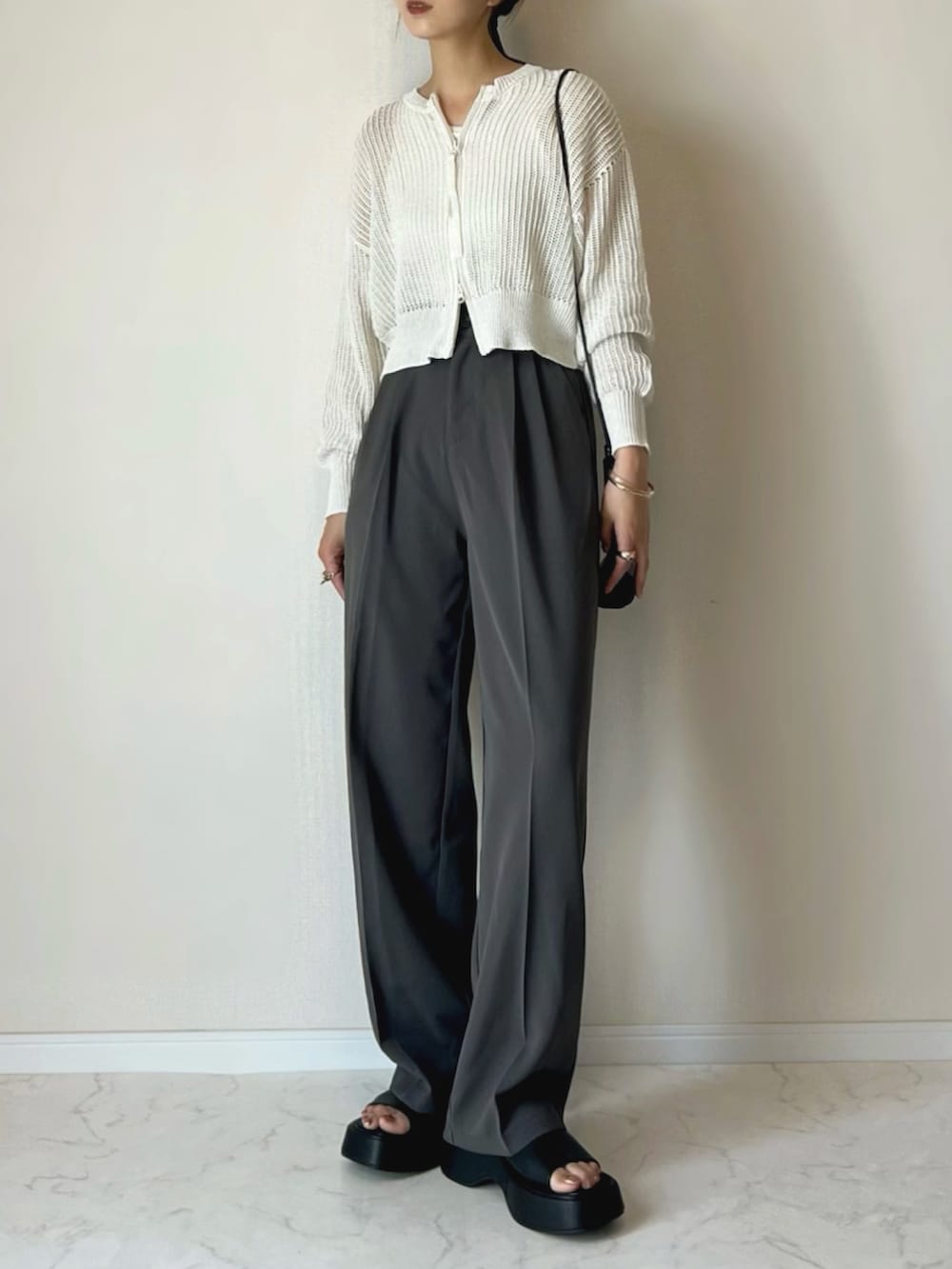 ホワイト系のカーディガン/ボレロ、グレー系のスラックス、ブラック系のサンダルを着用したレディースの夏コーディネートの2枚目の写真