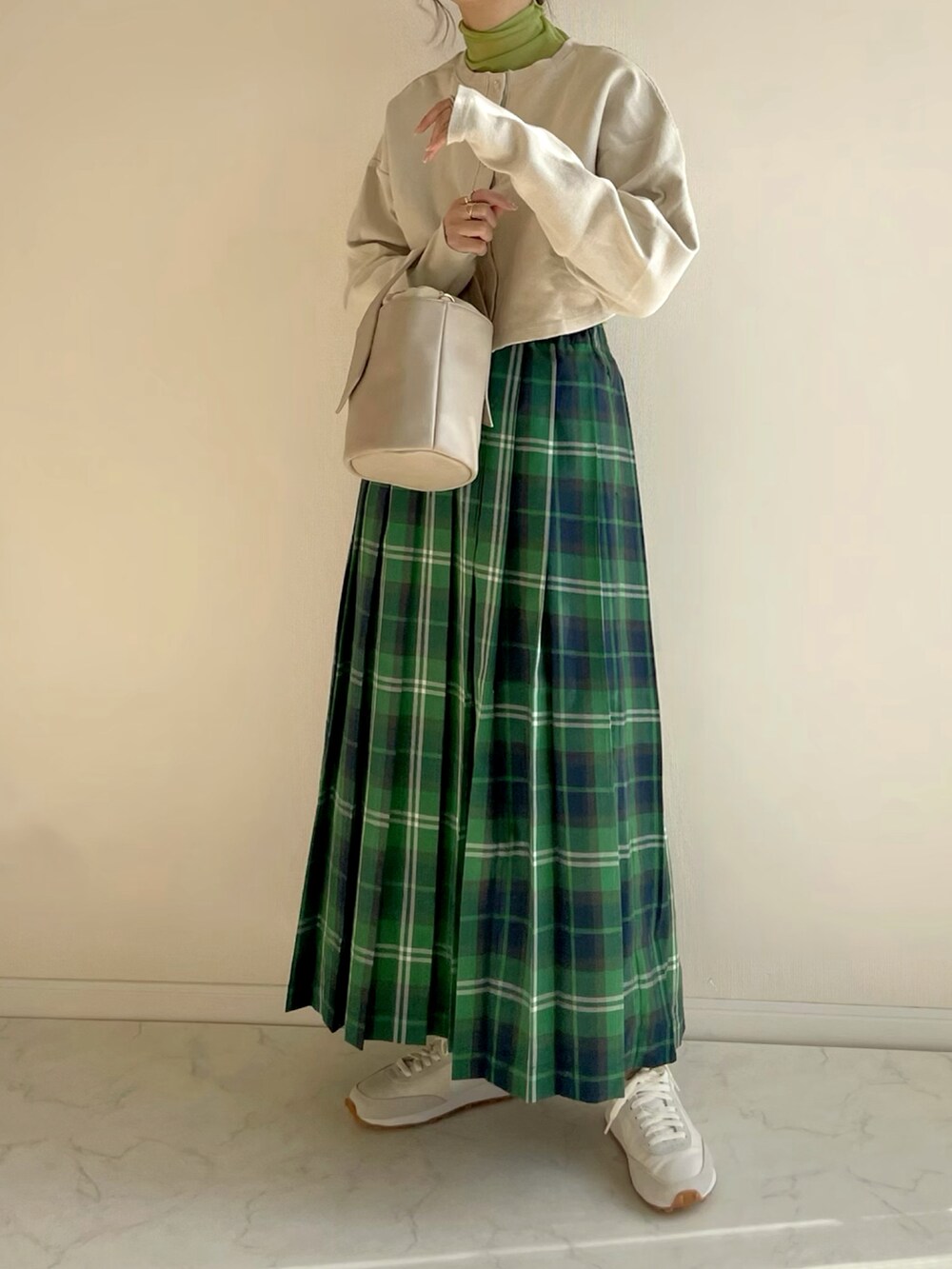 グリーン系のスカート、ベージュ系のカーディガン/ボレロ、グリーン系のTシャツ/カットソーを着用したレディースの冬コーディネートの2枚目の写真