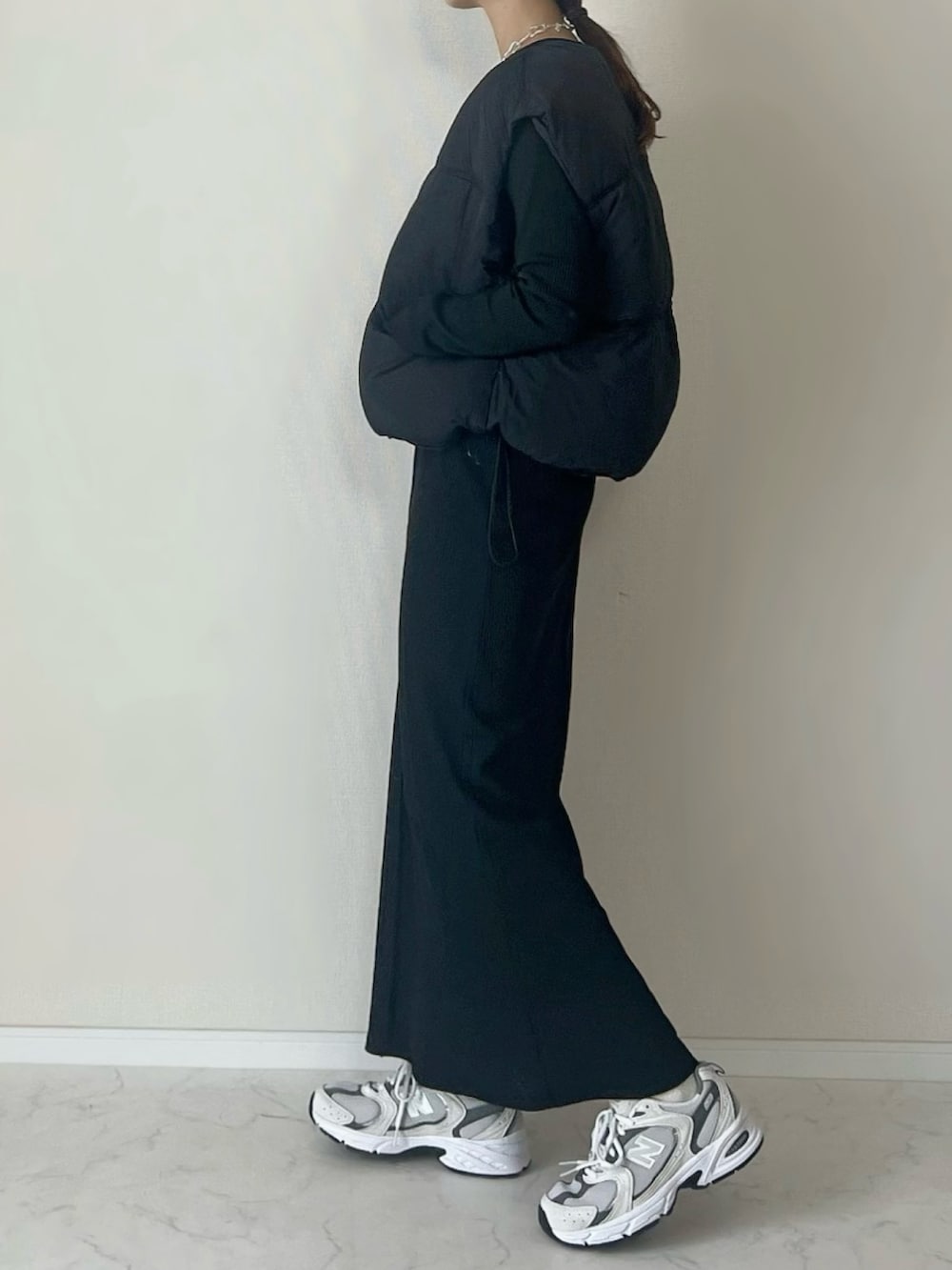 ブラック系のダウンベスト、グレー系のスニーカー、ブラック系のワンピース/ドレスを着用したレディースの冬コーディネートの3枚目の写真