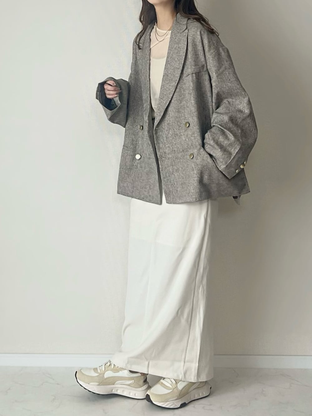 ベージュ系のテーラードジャケット、ホワイト系のスカート、ブラウン系のボストンバッグを着用したレディースの春コーディネートの2枚目の写真