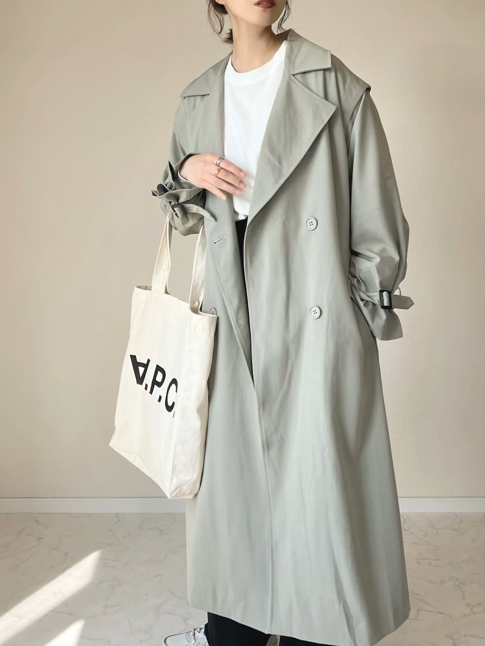 グリーン系のトレンチコート、ホワイト系のTシャツ/カットソー、ベージュ系のスニーカーを着用したレディースの春コーディネートの3枚目の写真