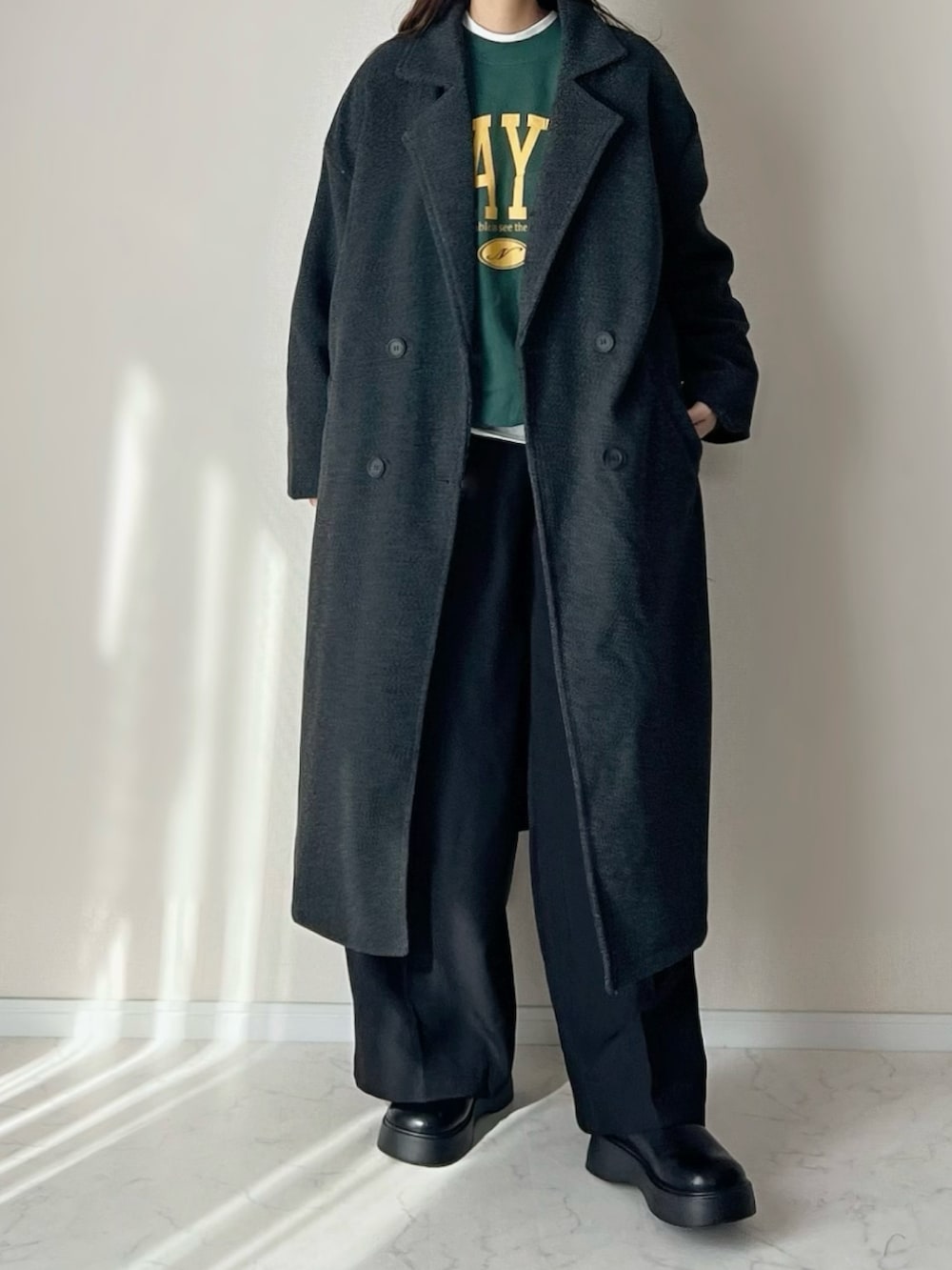 グレー系のチェスターコート、グリーン系のスウェットを着用したレディースの秋コーディネートの2枚目の写真