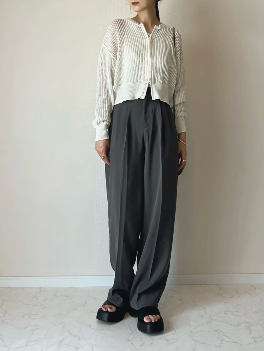 ホワイト系のカーディガン/ボレロ、グレー系のスラックス、ブラック系のサンダルを着用したレディースの夏コーディネートの3枚目の写真