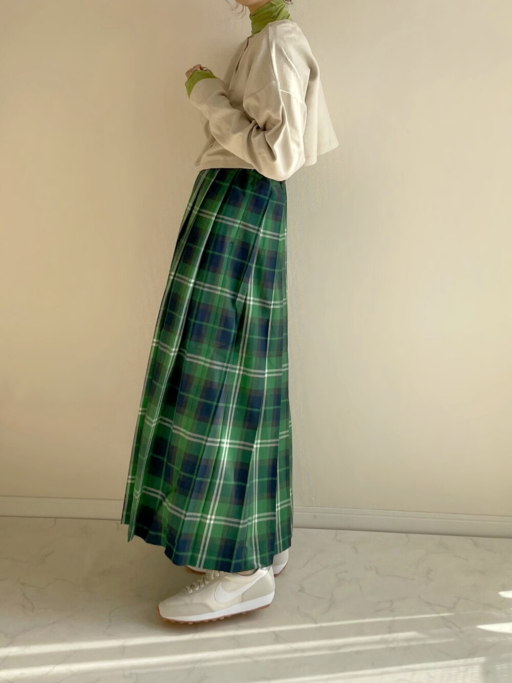 グリーン系のスカート、ベージュ系のカーディガン/ボレロ、グリーン系のTシャツ/カットソーを着用したレディースの冬コーディネートの4枚目の写真