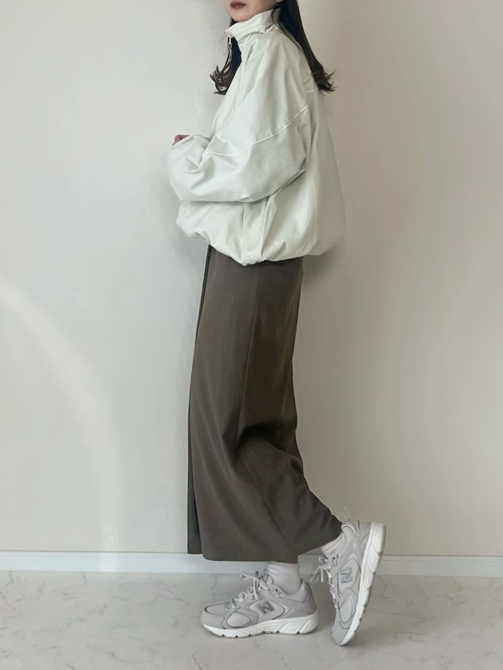 ホワイト系のブルゾン、ベージュ系のスニーカー、ベージュ系のキャップを着用したレディースの秋コーディネートの2枚目の写真