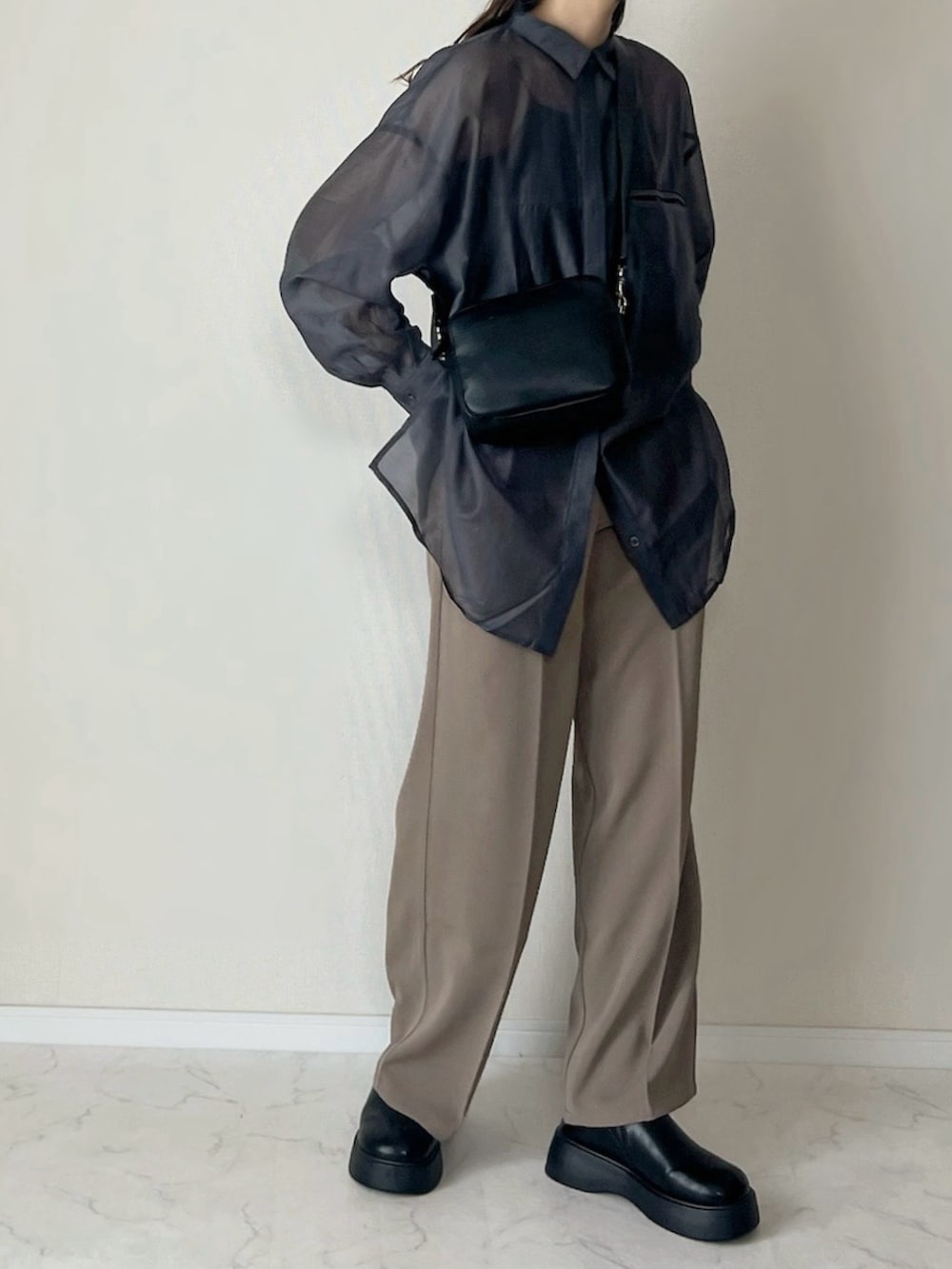 ベージュ系のスラックス、ブラック系のショルダーバッグ、ブラック系のスリッポンを着用したレディースの春コーディネートの2枚目の写真