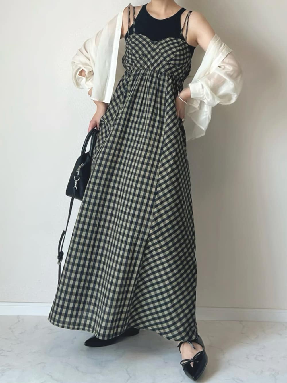 グリーン系のワンピース、ブラック系のサンダル、ブラック系のタンクトップを着用したレディースの春コーディネートの2枚目の写真