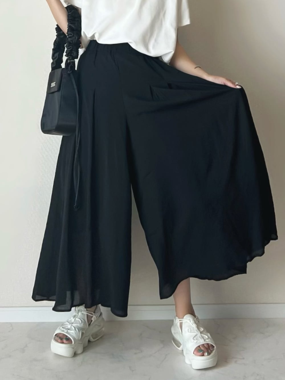 ブラック系のその他パンツ、ホワイト系のTシャツ/カットソー、ベージュ系のサンダルを着用したレディースの夏コーディネートの2枚目の写真