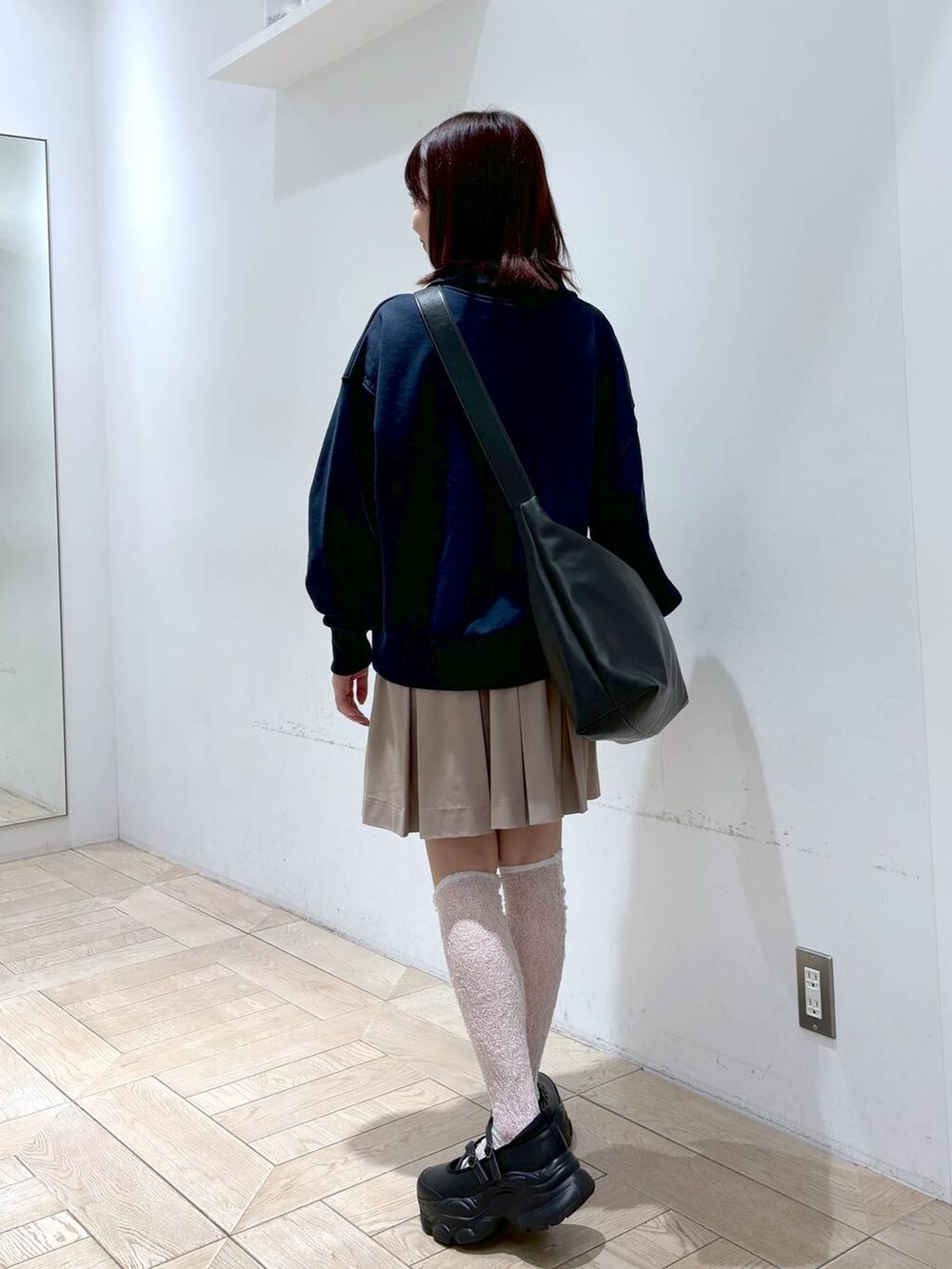 ブラック系のスニーカー、ブラック系のボディバッグ/ウエストポーチ、ホワイト系のスウェットを着用したレディースの秋コーディネートの2枚目の写真