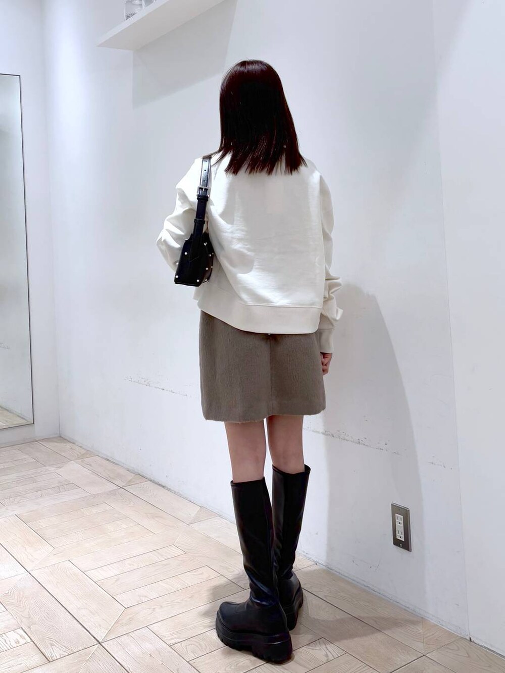 ブラック系のブーツ、ホワイト系のスウェット、ブラック系のショルダーバッグを着用したレディースの冬コーディネートの2枚目の写真