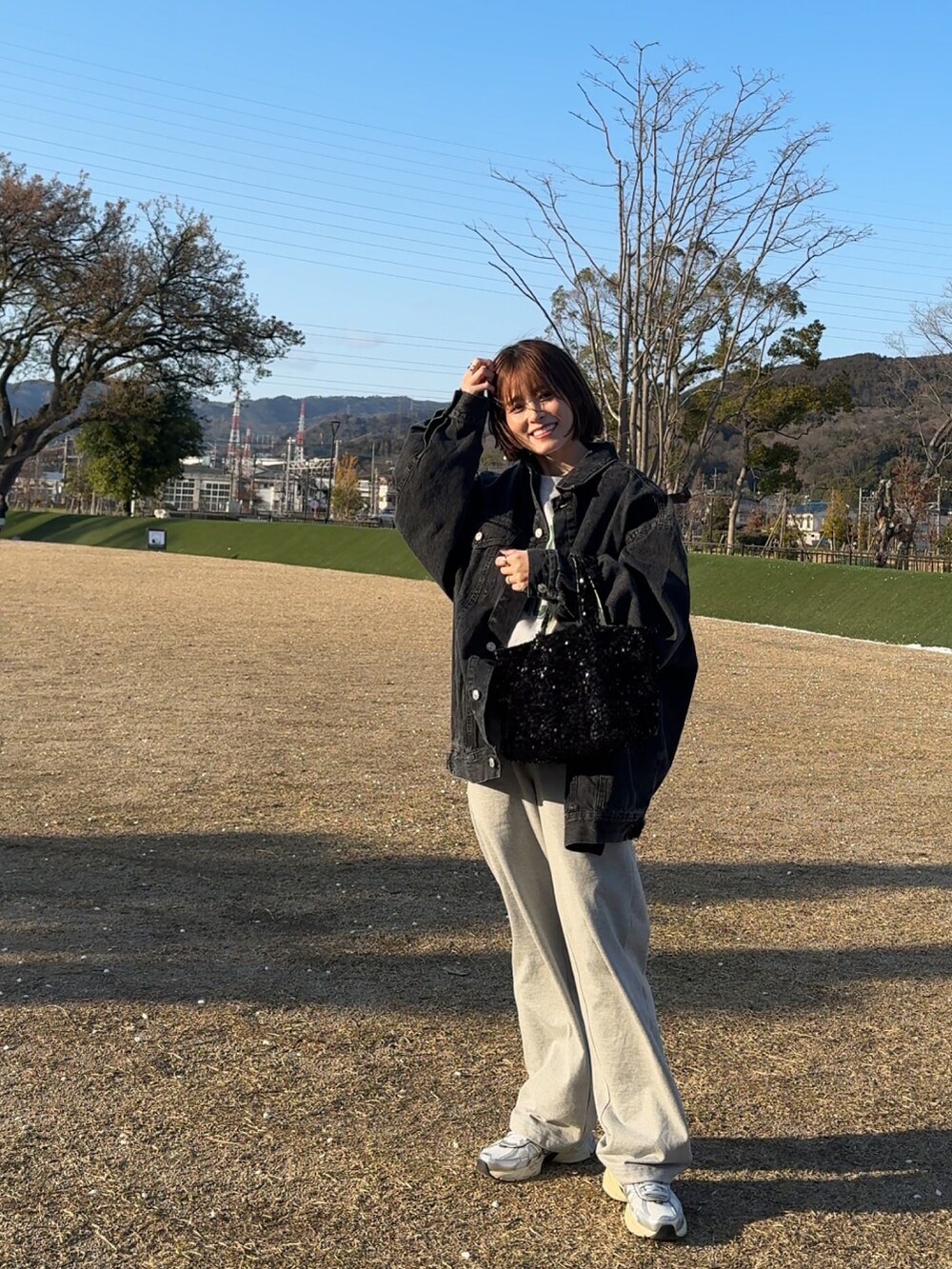 ブラック系のデニムジャケット、ブラック系のトートバッグ、グレー系のスウェットを着用したレディースの春コーディネートの2枚目の写真