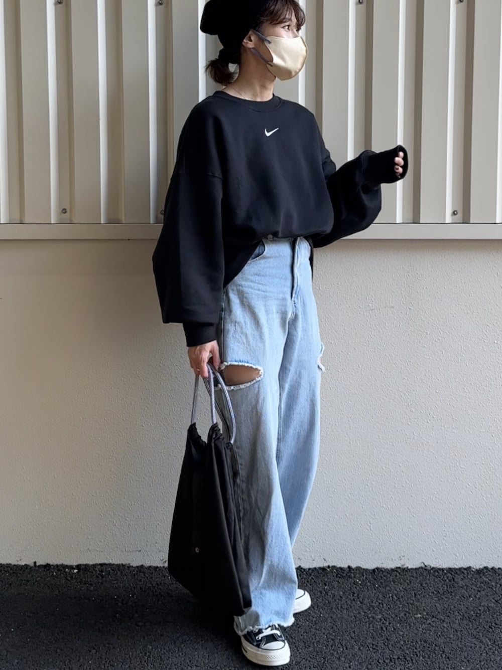 ブラック系のスウェット、ブルー系のデニムパンツ、ブラック系のエコバッグ/サブバッグを着用したレディースの秋コーディネートの2枚目の写真