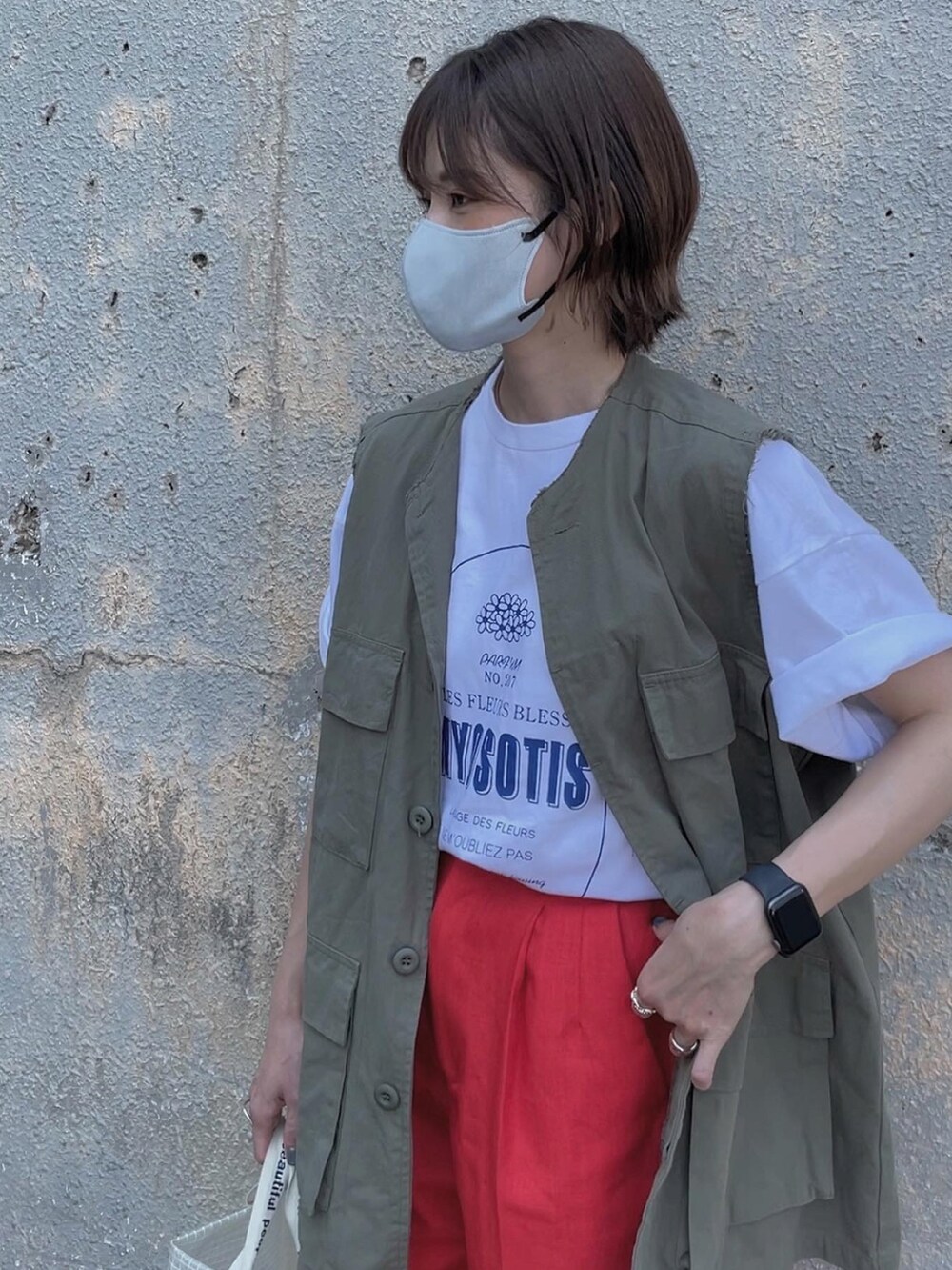 グリーン系のベスト、ホワイト系のショルダーバッグ、グリーン系のスニーカーを着用したレディースの夏コーディネートの2枚目の写真