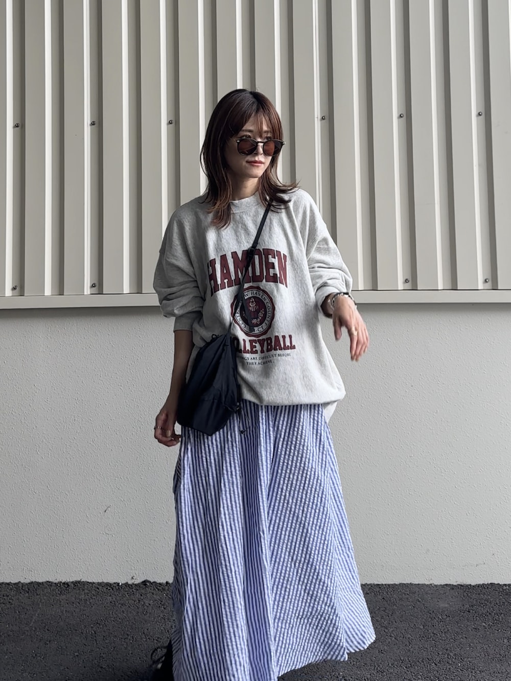 グレー系のスウェット、ブラック系のショルダーバッグ、ブラック系のスニーカーを着用したレディースの夏コーディネートの3枚目の写真