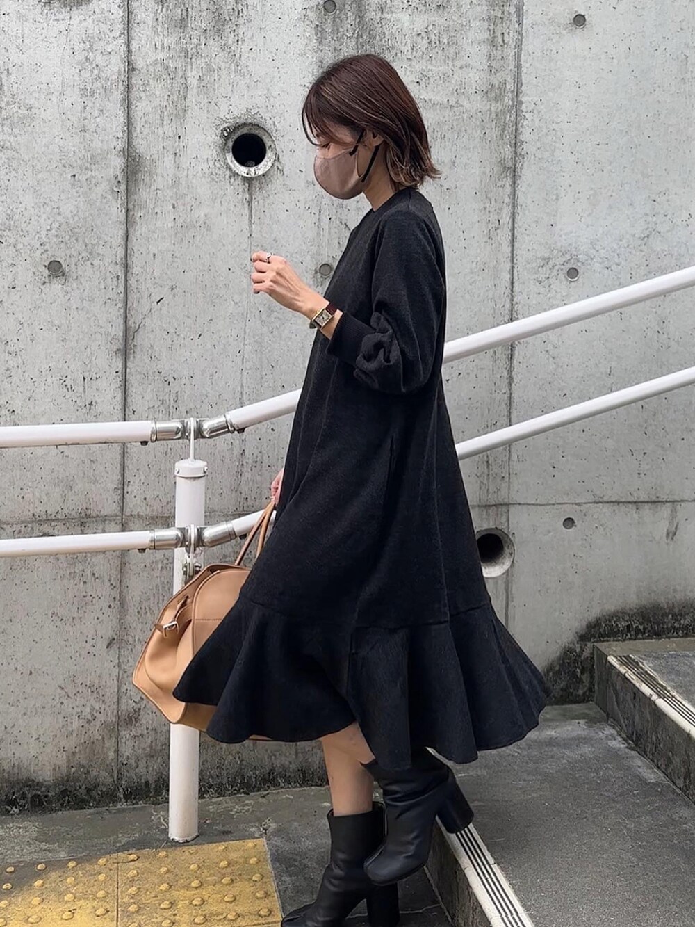 グレー系のワンピース、ブラック系のベストを着用したレディースの秋コーディネートの3枚目の写真