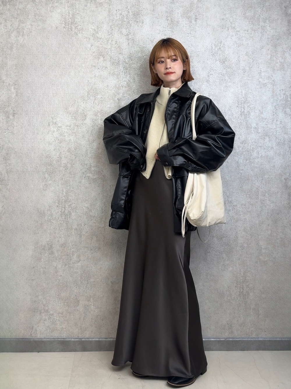 ブラック系のブルゾン、ホワイト系のカーディガン/ボレロ、ホワイト系のトートバッグを着用したレディースの春コーディネートの2枚目の写真