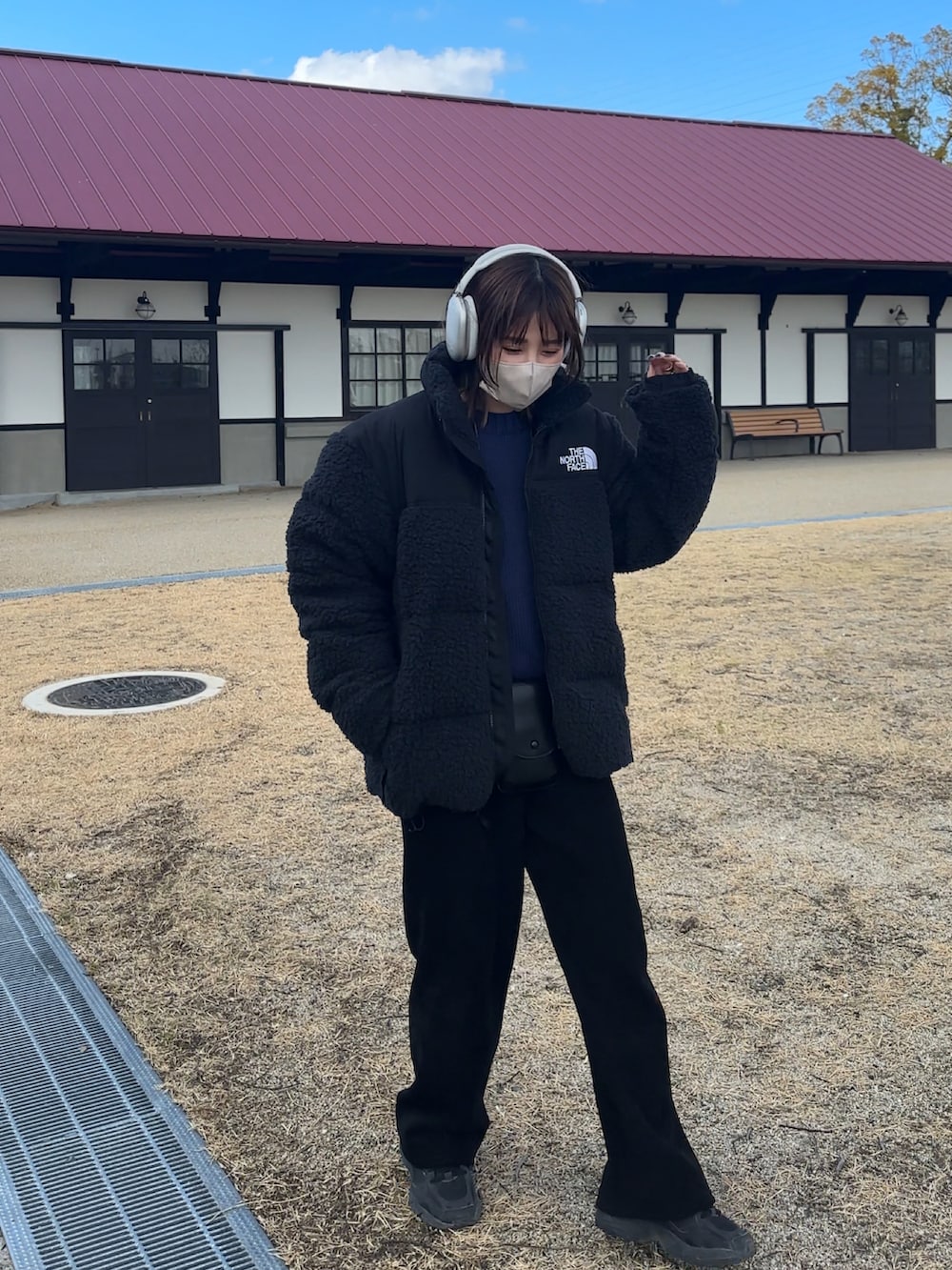 ブラック系のジャケット/アウター、ブルー系のニット/セーター、ブラック系のスニーカーを着用したレディースの冬コーディネートの2枚目の写真