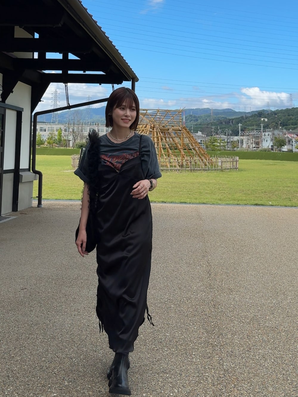 ブラック系のブーツ、ブラック系のショルダーバッグ、ブラック系のワンピースを着用したレディースの夏コーディネートの2枚目の写真