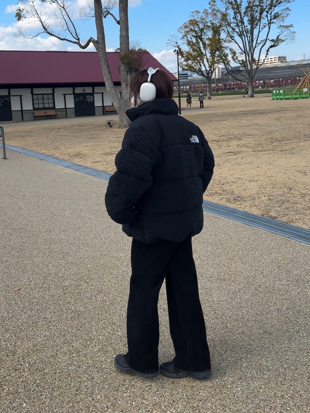 ブラック系のジャケット/アウター、ブルー系のニット/セーター、ブラック系のスニーカーを着用したレディースの冬コーディネートの3枚目の写真