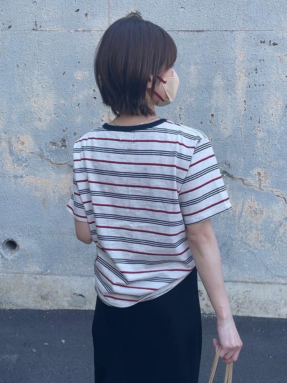 ベージュ系のトップス、ブラック系のスカート、イエロー系のトートバッグを着用したレディースの春コーディネートの3枚目の写真