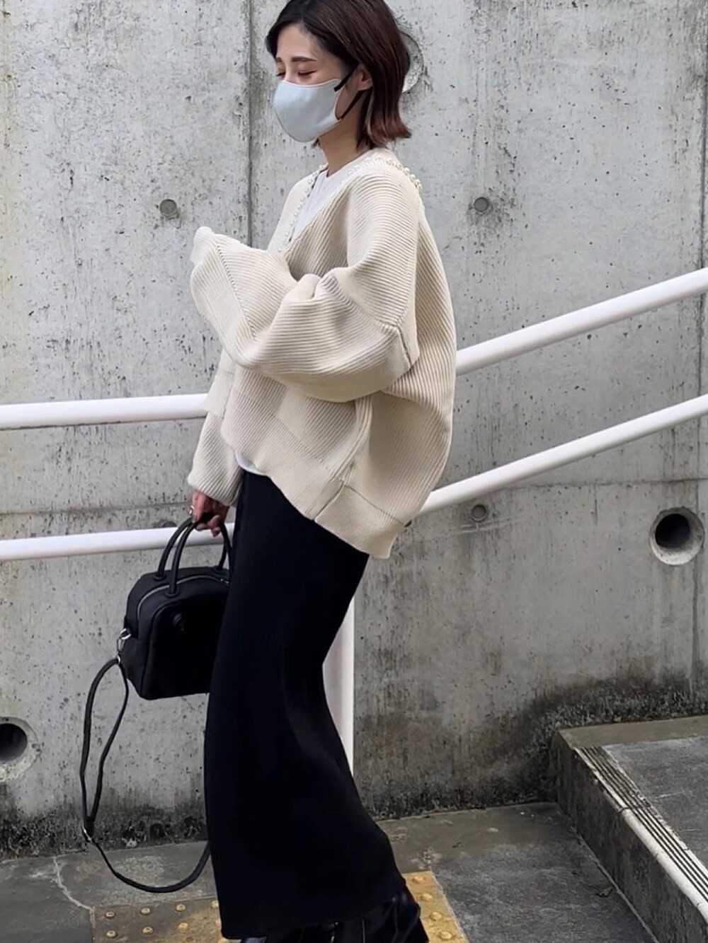 ベージュ系のカーディガン/ボレロ、ブラック系のブーツを着用したレディースの秋コーディネートの2枚目の写真