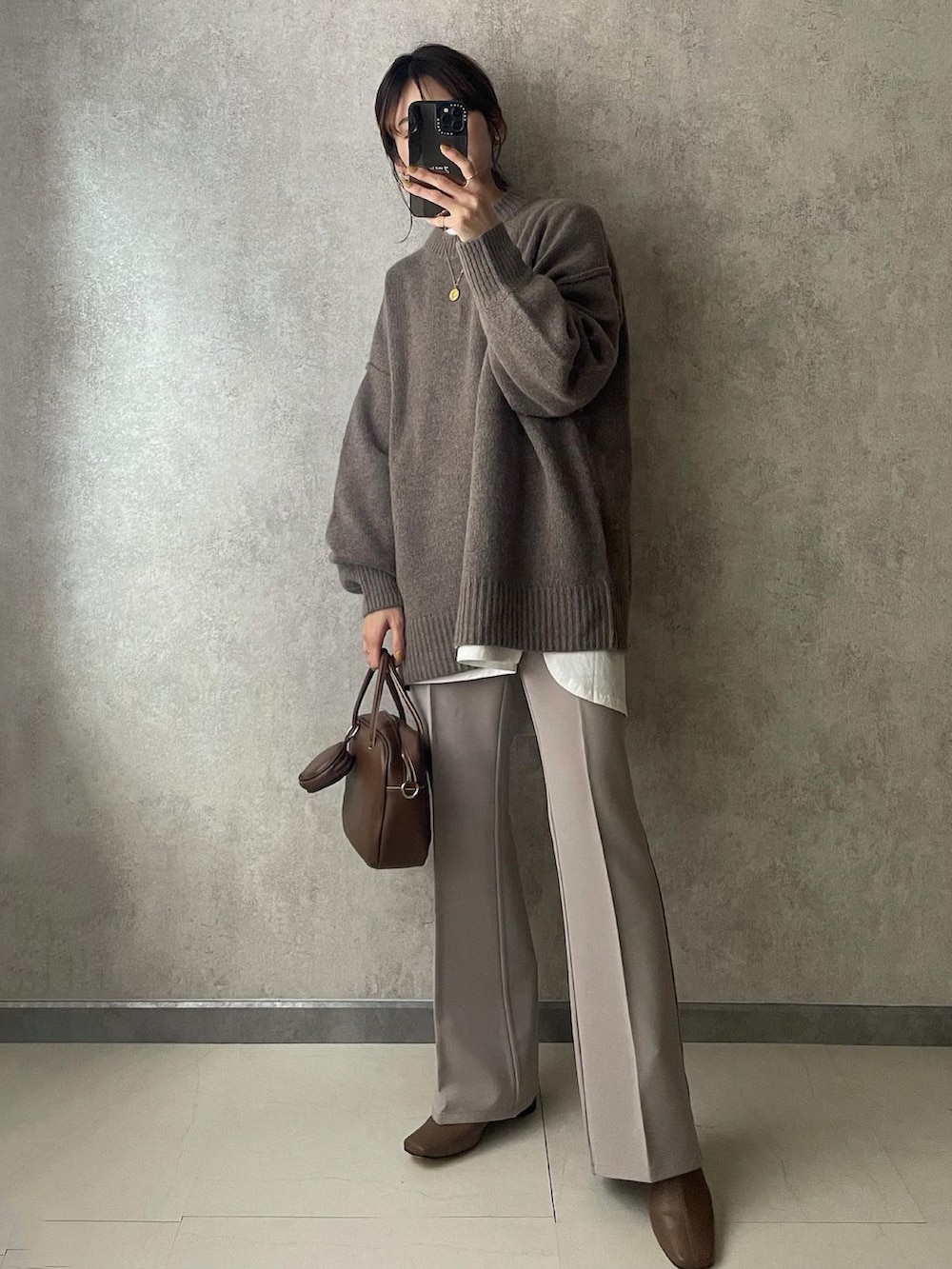 グレー系のニット/セーター、ホワイト系のTシャツ/カットソー、ブラウン系のブーツを着用したレディースの秋コーディネートの2枚目の写真