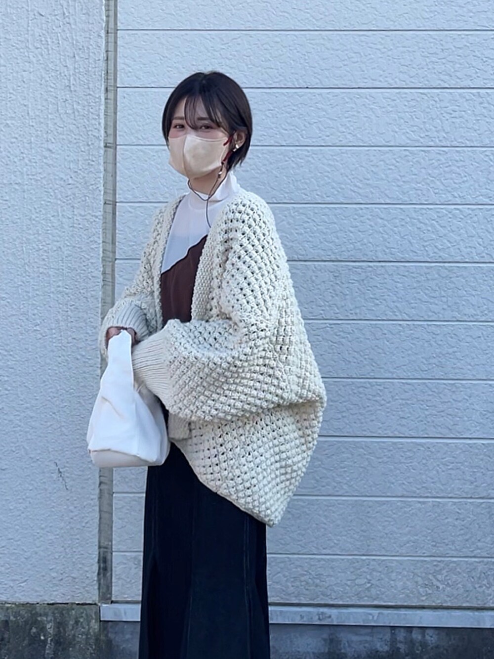 ブルー系のスカート、ブラック系のブーツ、ホワイト系のカーディガン/ボレロを着用したレディースの冬コーディネートの2枚目の写真