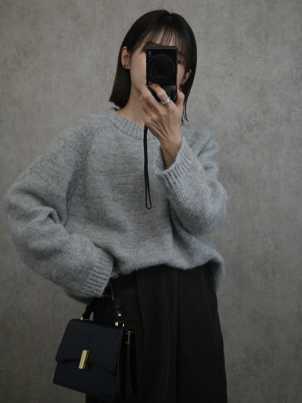 グレー系のニット/セーター、ブラック系のショルダーバッグを着用したレディースの秋コーディネートの2枚目の写真
