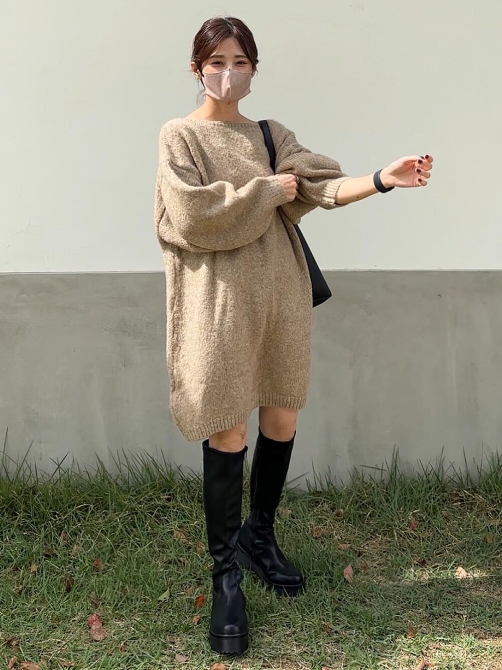 ベージュ系のワンピース、ブラック系のブーツを着用したレディースの秋コーディネートの2枚目の写真