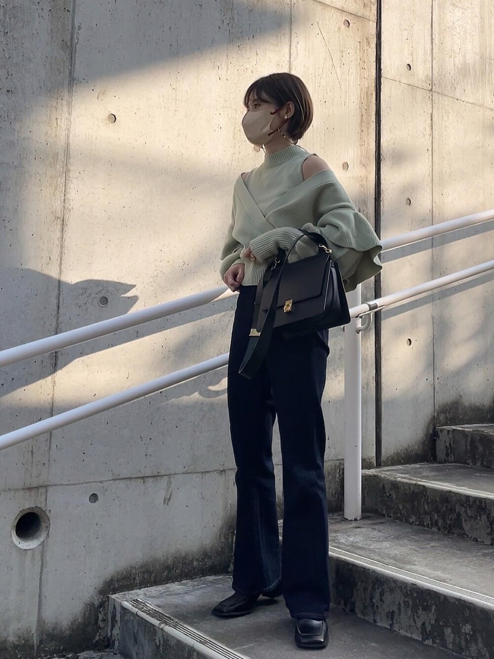 グリーン系のニット/セーター、ブラック系のブーツを着用したレディースの冬コーディネートの2枚目の写真