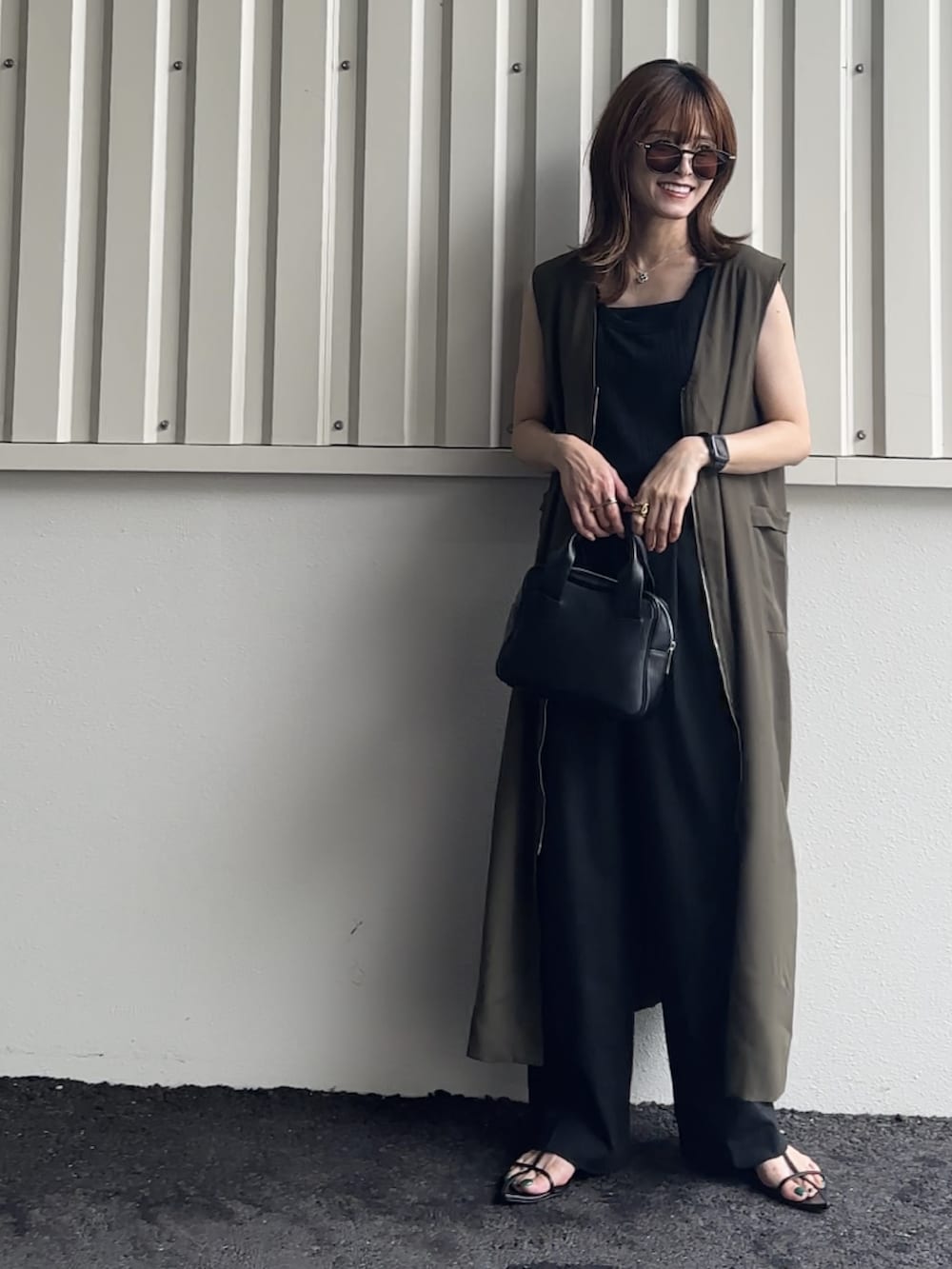 グリーン系のジャンパースカート、ブラック系のTシャツ/カットソー、ブラック系のサンダルを着用したレディースの夏コーディネートの2枚目の写真