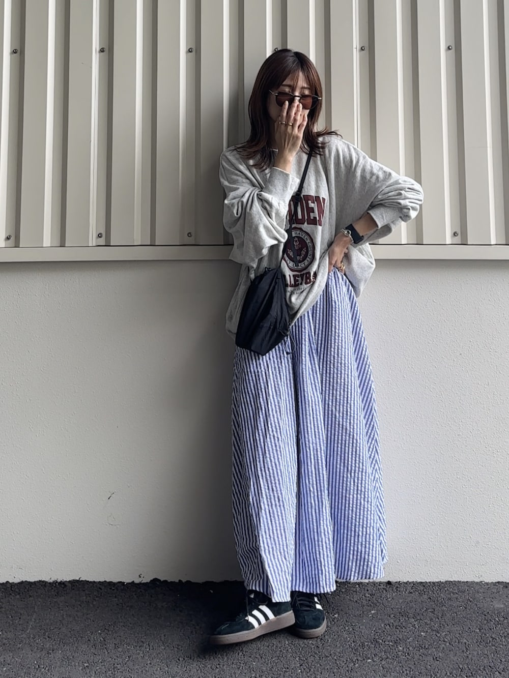 グレー系のスウェット、ブラック系のショルダーバッグ、ブラック系のスニーカーを着用したレディースの夏コーディネートの2枚目の写真