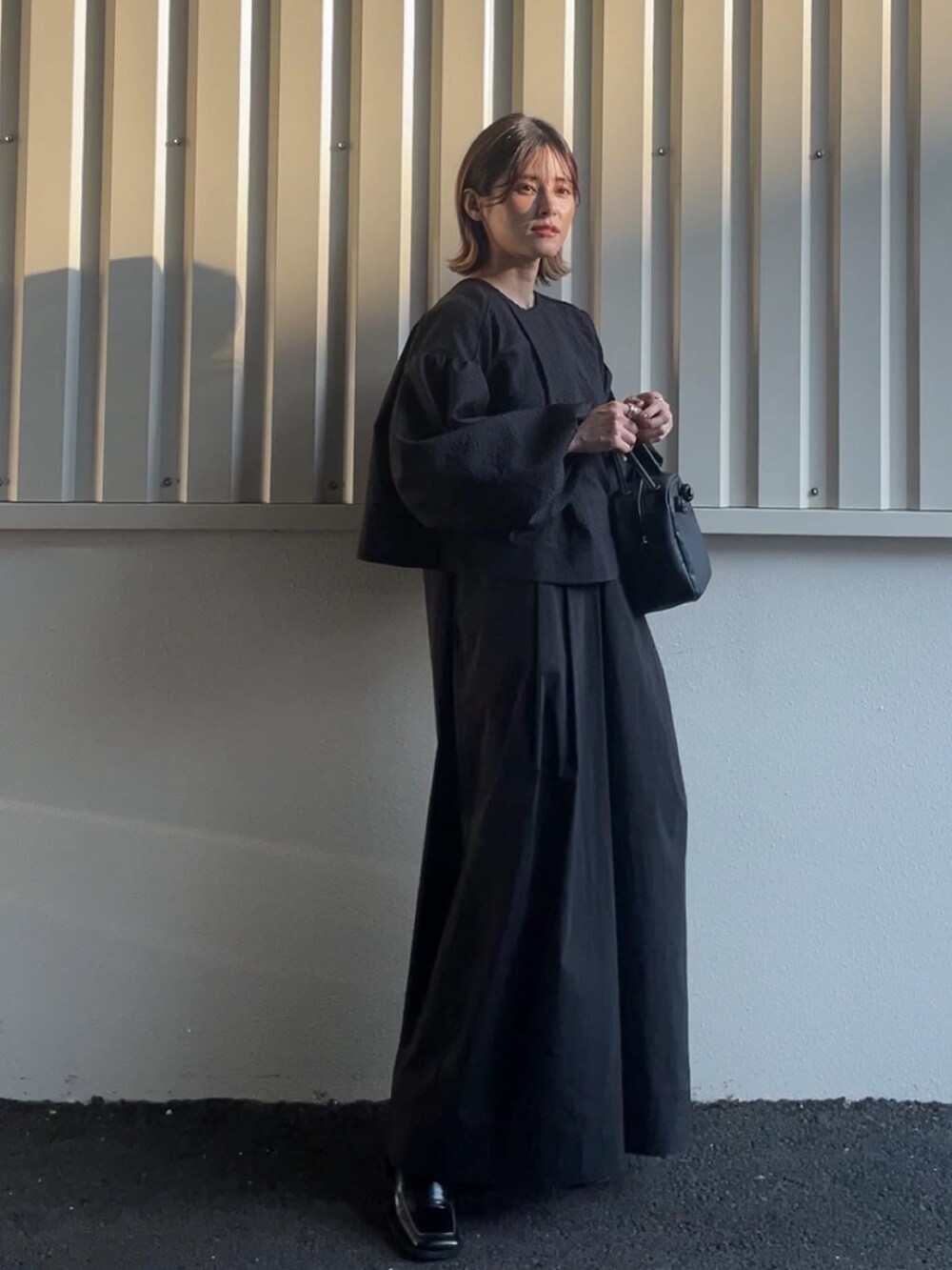 ベージュ系のワンピース、ブラック系のブーツを着用したレディースの秋コーディネートの2枚目の写真