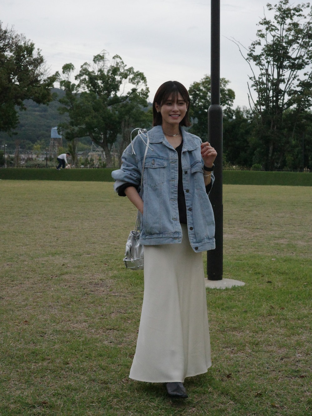 ブルー系のデニムジャケット、ブラック系のスウェット、ホワイト系のスカートを着用したレディースの秋コーディネートの2枚目の写真