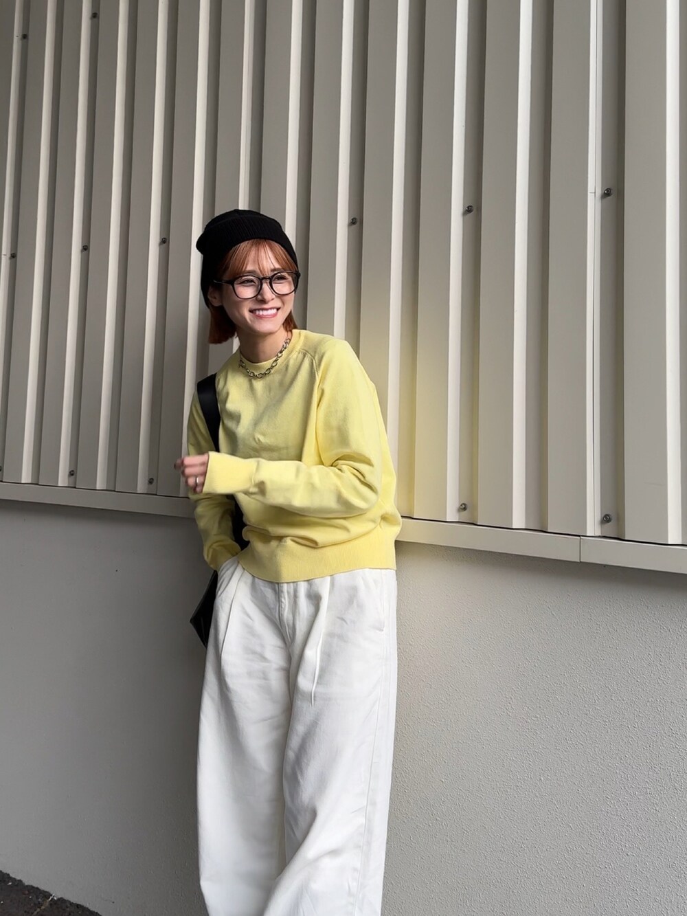 イエロー系のニット/セーター、ブラック系のニットキャップ/ビーニーを着用したレディースの冬コーディネートの2枚目の写真