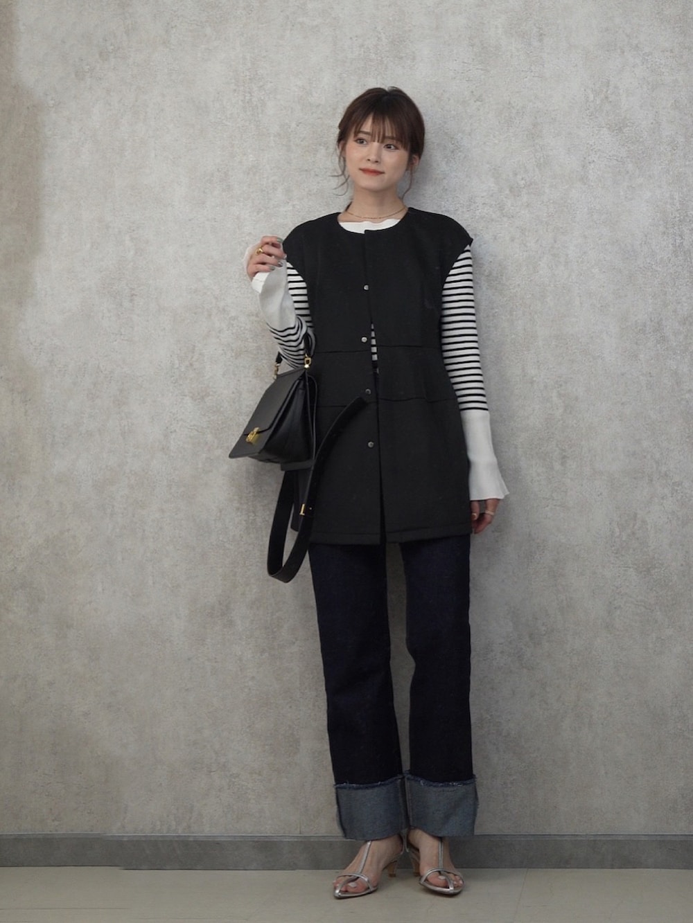 ブラック系のベスト、ブルー系のデニムパンツ、シルバー系のサンダルを着用したレディースの春コーディネートの4枚目の写真