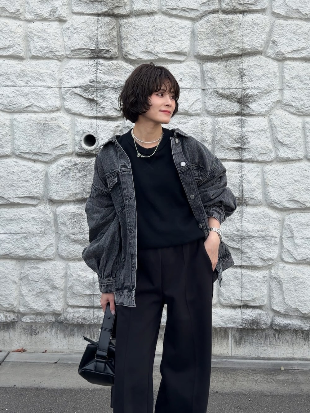 ブラック系のデニムジャケット、ブラウン系のショルダーバッグを着用したレディースの冬コーディネートの2枚目の写真