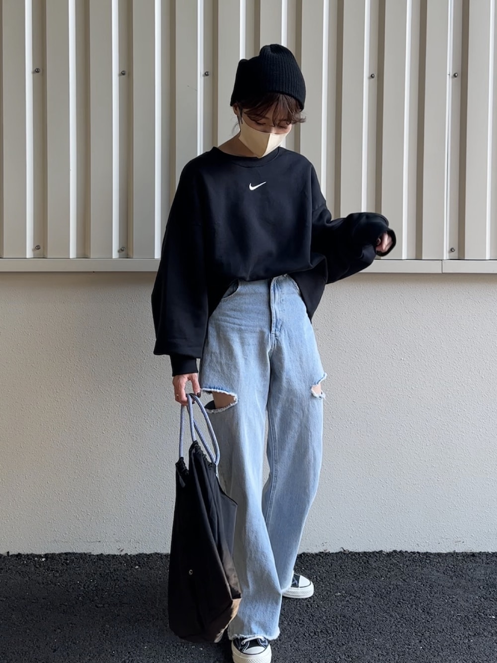 ブラック系のスウェット、ブルー系のデニムパンツ、ブラック系のエコバッグ/サブバッグを着用したレディースの秋コーディネートの3枚目の写真