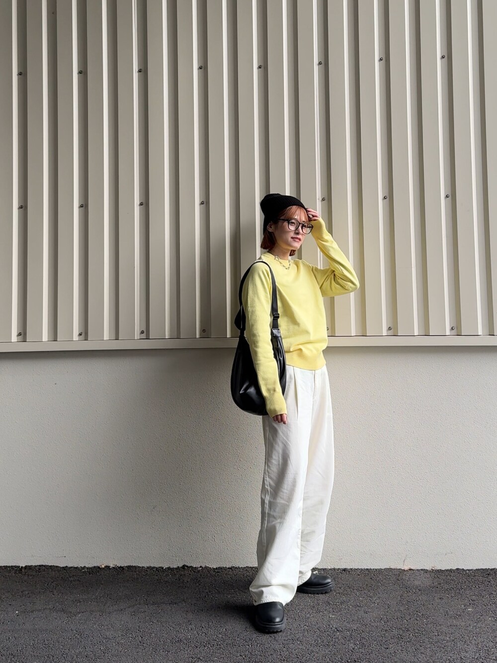 イエロー系のニット/セーター、ブラック系のニットキャップ/ビーニーを着用したレディースの冬コーディネートの3枚目の写真