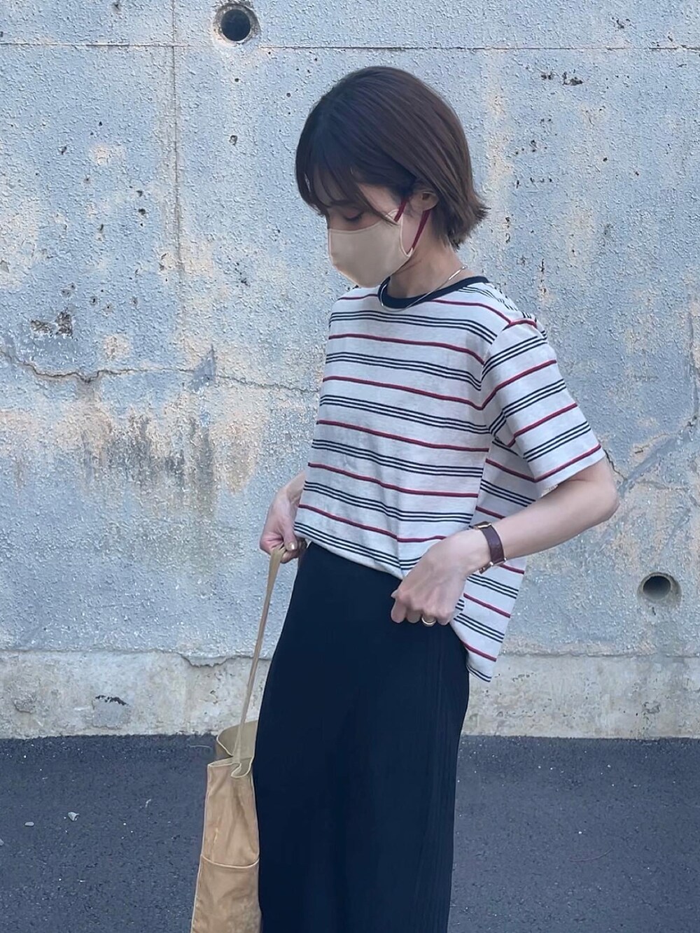 ベージュ系のトップス、ブラック系のスカート、イエロー系のトートバッグを着用したレディースの春コーディネートの2枚目の写真