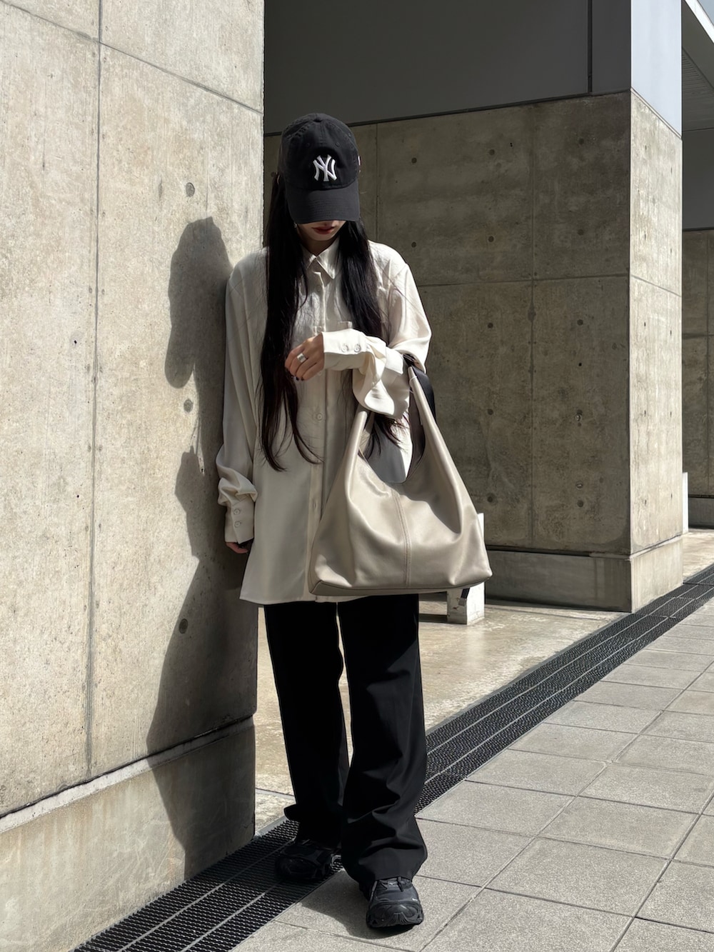 ブラック系のスニーカー、ベージュ系のショルダーバッグを着用したレディースの春コーディネートの3枚目の写真